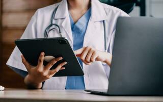 medisch dokter of arts overleg plegen patiënten Gezondheid online gebruik makend van internet mobiel digitaal tablet in kliniek of ziekenhuis kantoor voor professioneel noodgeval gezondheidszorg bijstand onderhoud concept foto