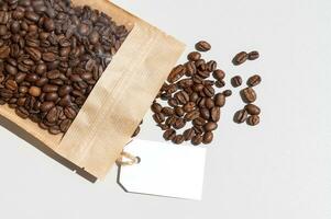 koffie bonen liggen met een papier kraft zak en een mock-up van een wit label foto