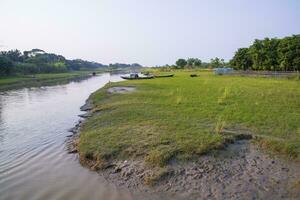 kanaal met groen gras en vegetatie weerspiegeld in de water in de buurt padma rivier- in Bangladesh foto