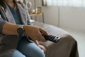 dichtbij omhoog televisie afgelegen controle in hand- vrouw richten naar TV reeks en draaien het Aan of uit. selecteer kanaal aan het kijken TV Bij huis in de leven kamer kom tot rust. foto