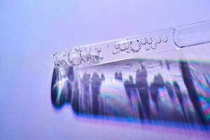 transparant pipet met serum met bubbels in Purper licht. foto
