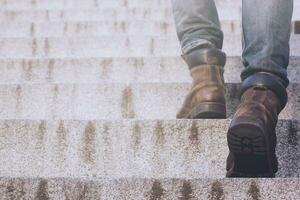 dichtbij omhoog poten van jong hipster Mens een persoon wandelen stepping gaan omhoog de trap in modern stad, Gaan omhoog, succes, toenemen omhoog. met filter tonen retro wijnoogst warm effect. foto