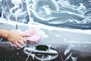 mensen man met hand roze spons voor het wassen van de auto. wielband schoonmaken. concept carwash schoon. foto