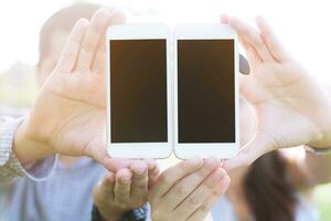 jong mannetje vrienden groep zitten vergadering uitwisseling telefoontje mobiel slim telefoon aantal en sturen bericht in buitenshuis openbaar park. delen aansluiten Bluetooth. sociaal afstand nemen. nieuw normaal. foto