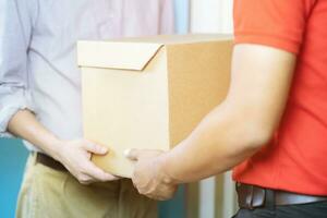 huis levering, online bestellen. een Mens in uniform, een medisch masker en rubber handschoenen met een doos foto