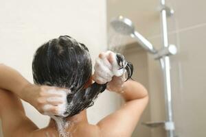 vrouw nemen douche en het wassen haar- met shampoo foto