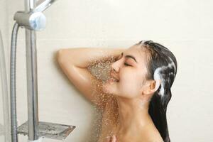 vrouw nemen douche en het wassen haar- met shampoo foto