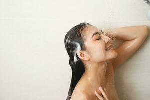 vrouw nemen douche en het wassen haar- met shampoo foto