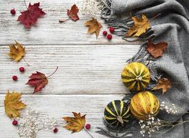 herfst esdoorn bladeren, pompoenen en wollen sjaal op een houten ondergrond. foto