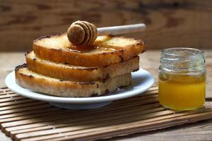 drie gebakken toast met honing op een houten achtergrond foto