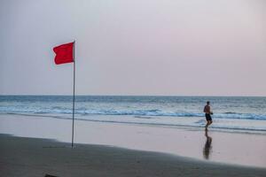 rood vlag Aan strand Aan zee of oceaan Bij zonsondergang net zo symbool van Gevaar. de zee staat is beschouwd gevaarlijk en zwemmen is verboden. foto