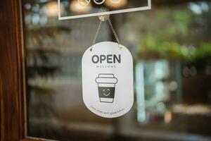 Open teken breed door de deur glas bokeh achtergrond. Open teken bord door de glas van op te slaan venster. tekst houten bord deur wijnoogst winkel teken geopend op te slaan. foto