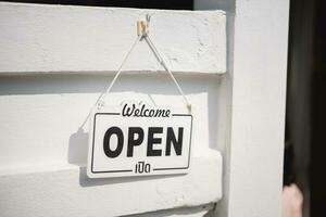 Open teken breed door de wit muur achtergrond. Open teken bord door de glas van op te slaan venster. wit tekst houten bord deur wijnoogst winkel teken geopend op te slaan. foto