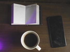 bovenaanzicht artistieke koffie notebook en mobiele telefoon houten tafel foto