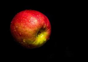 waterdruppel op glanzend oppervlak van rode appel op zwarte achtergrond foto