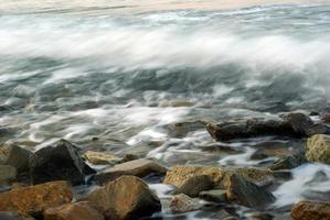 turbulentie zeewater en rots aan de kust foto