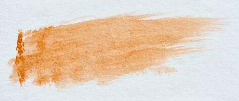een beroerte van oranje waterverf verf Aan een wit vel van papier foto