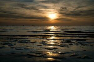 zonsondergang, klein rots Bij laag tij in voorkant van de verlichte zee. Baltisch zee. foto