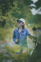 mooi vrouw vervelend blauw jeans jasje zittend Aan enduro motorfiets tegen kleurrijk natuurlijk achtergrond foto