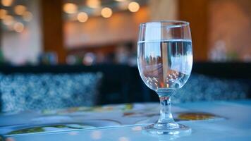 luxe glas met water Aan vervagen goud lichten bokeh achtergrond Aan de bar en hotel foto