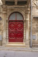 beeld van een rood Ingang deur naar een woon- gebouw met een antiek facade foto