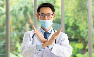 jonge Aziatische dokter laat zien hoe je een masker correct draagt via podcast online foto