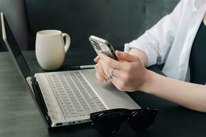 professioneel onderneemsters multitasking met laptops en smartphones in modern kantoor. verschillend vrouw managers verloofd in internet afzet Bij kantoor werkplekken. smartphone-aangedreven werk. foto