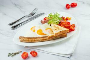 door elkaar gegooid eieren met groenten, kers tomaten, brood, kruiden en worstjes Aan een wit bord kant visie foto