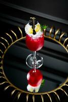 rood cocktail Aan een donker achtergrond met geslagen room topping kant visie foto