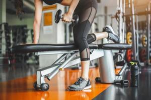 jonge vrouw bankdrukken met halters in fitness gym