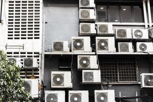 veel vuile oude airconditioners op een vuile muur. foto