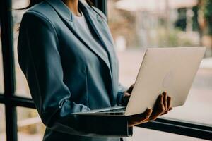 aantrekkelijk glimlachen jong Aziatisch bedrijf vrouw werk Bij huis kantoor, Aziatisch vrouw werken Aan laptop computer Holding tablet. foto