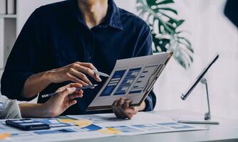 dichtbij omhoog ux ontwikkelaar en ui ontwerper brainstorming over mobiel app koppel wireframe ontwerp Aan tafel met klant breif en kleur code Bij modern kantoor.creatief digitaal ontwikkeling agentschap foto