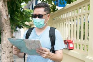 toerist die gezondheidsmaskers draagt en kaart vasthoudt voor reisplanning foto