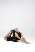 een mooi slank gymnast in een rekken in een trainingspak doet sport- of yoga in de studio uitrekken foto