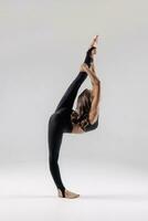 een mooi slank gymnast in een rekken in een trainingspak doet sport- of yoga in de studio uitrekken foto