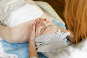 mooi jong vrouw ontvangen gelaats massage met Gesloten ogen in een spa salon foto