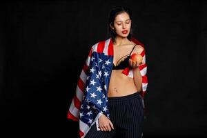 portret vrouw atleet verpakt in Amerikaans vlag tegen zwart achtergrond foto