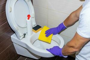 huishoudster met beschermend handschoenen in handen schoonmaak badkamer foto