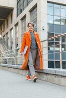 stijlvolle dame in fel oranje jas in een stad scène foto