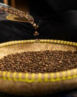 koffie bonen zijn gegoten van een koffie lepel in een stapel van geroosterd koffie bonen in de midden- van de roosteren qc kwaliteit controle werkwijze foto