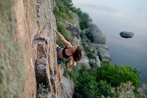 een meisje klimt een steen. vrouw verloofd in extreem sport. foto