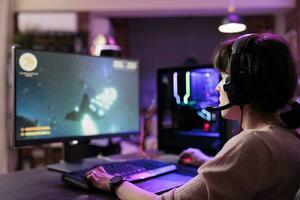 professioneel gamer innemend in online competitief multiplayer toernooi gebruik makend van snijdend rand gaming systeem, boeiend fans gedurende leven stroom. vrouw in rgb lichten lit leven kamer spelen computerspelletjes foto