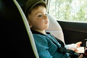 kleuter jongen zittend in kind veiligheid stoel in auto. auto op reis met kind. foto