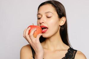 gezond aan het eten. vrouw bijten rood appel met perfect tanden foto