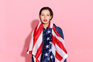 portret vrouw atleet verpakt in Amerikaans vlag tegen roze achtergrond foto