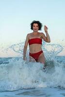 sexy terug van een mooi vrouw in rood bikini Aan zee achtergrond foto