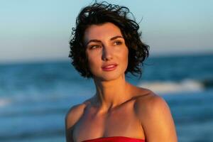 sexy terug van een mooi vrouw in rood bikini Aan zee achtergrond foto