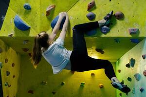 jong vrouw beklimming omhoog Aan praktijk muur in Sportschool foto