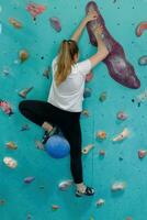 jong vrouw beklimming omhoog Aan praktijk muur in Sportschool foto